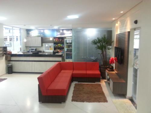 un sofá rojo en la sala de estar con cocina en Hotel Guarumar, en Guarujá