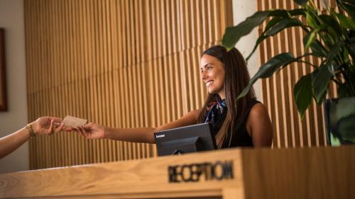 a woman handing another woman a piece of paper at Hotel Admiral in Budva