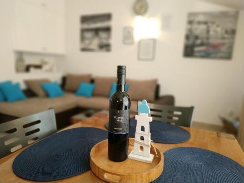 a bottle of wine and a toy lighthouse on a table at Promaja in Okrug Donji