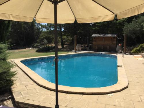 un parasol assis à côté d'une piscine dans l'établissement Le Jas des Vignes, à Lirac