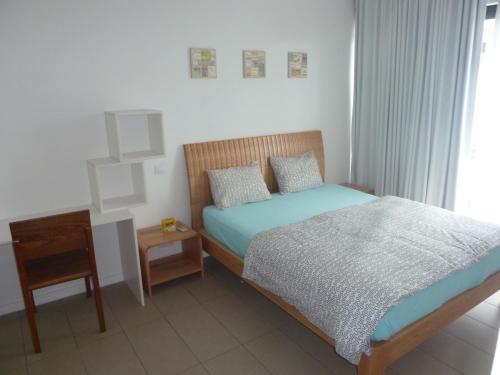 a bedroom with a bed and a night stand and a window at Swiss Nest Travel in Roches Noires