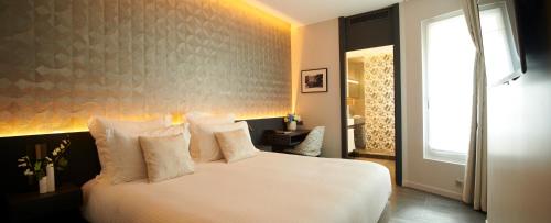 a bedroom with a bed with white pillows and a window at Hôtel Roi de Sicile - Rivoli in Paris