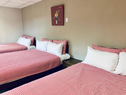 a room with three beds with red and white sheets at Puli Islet Inn in Puli