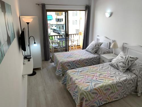 Habitación de hotel con 2 camas y TV en Cozy Studio in Los Cristianos Beach FREE WIFI, en Arona