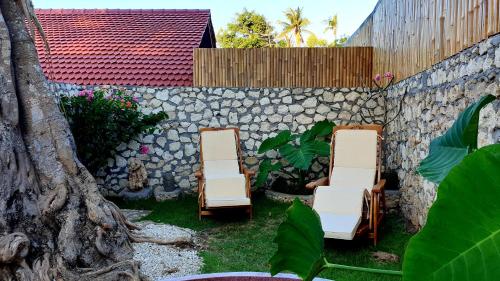 two chairs in a yard next to a stone wall at Jungle Paradise in Nusa Penida