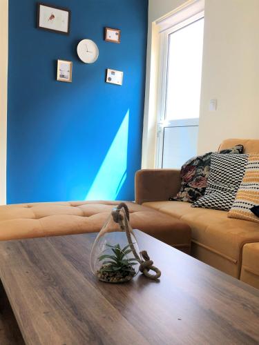 a living room with a table and a blue wall at Boho Apartment near Athens Airport in Spáta