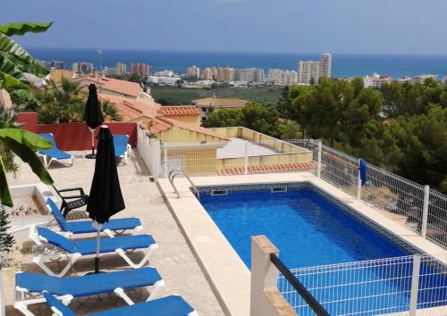 a view of a swimming pool and chairs and the ocean at Apartamentos Panoramica in Peniscola