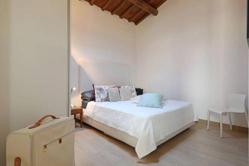- une chambre blanche avec un lit et une valise dans l'établissement Luxury House Colosseo, à Rome