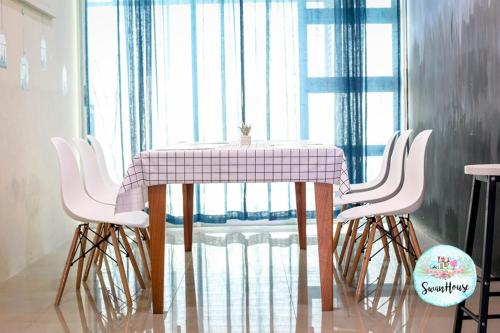 una mesa con 4 sillas blancas y una mesa rosa y blanca en Sibu Swanhouse NO.IV (Full House), en Sibu