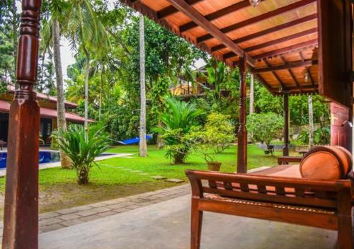 a wooden bench sitting under a wooden pergola at Araliya Gardens Hotel in Hikkaduwa