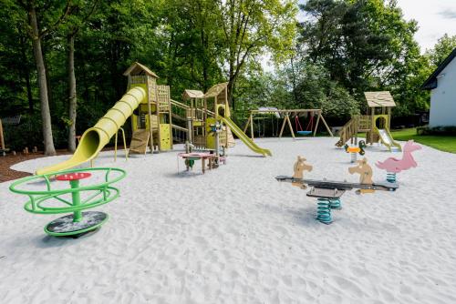 a playground with slides and play equipment in the sand at Charmehotel Klokkenhof in Brasschaat
