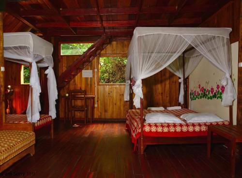a bedroom with two beds in a room with wooden floors at Les Acacias Bungalows in Manambato