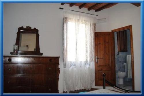 a bedroom with a dresser and a window with a mirror at Fra I Mesi in Ambra