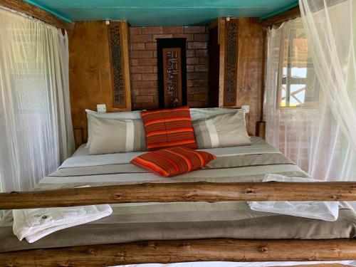 a bed with two pillows on it in a room at Samuka Island Retreat in Jinja