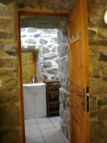 une salle de bain avec un lavabo et un mur en pierre dans l'établissement Les jardins de la Volane, à Vals-les-Bains
