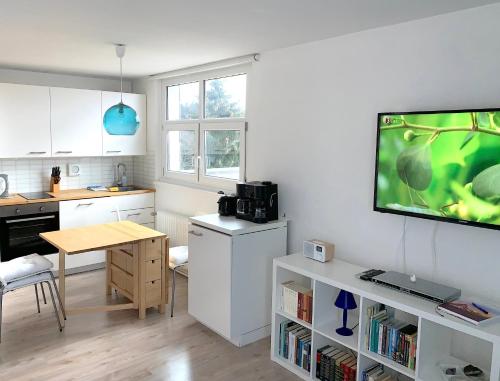 een keuken met een tafel en een tv aan de muur bij Alpenblick in Sankt Englmar