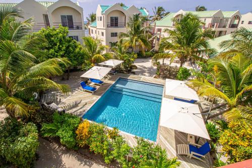an aerial view of a resort pool with umbrellas and palm trees at Tres Cocos Resort in San Pedro