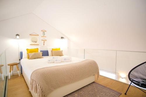 a bedroom with a large white bed with yellow pillows at Feel Nazaré - Boutique Apartments in Nazaré