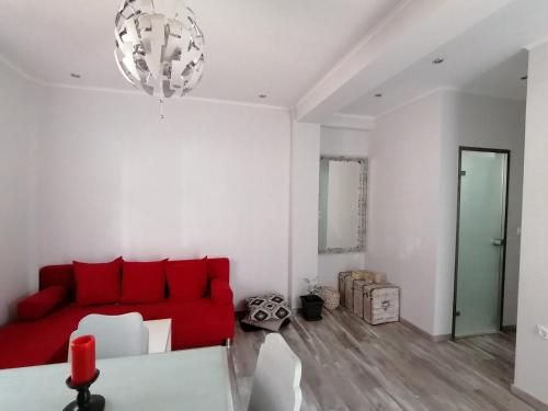a living room with a red couch and a chandelier at "ΙωΚαρ" in Nafpaktos