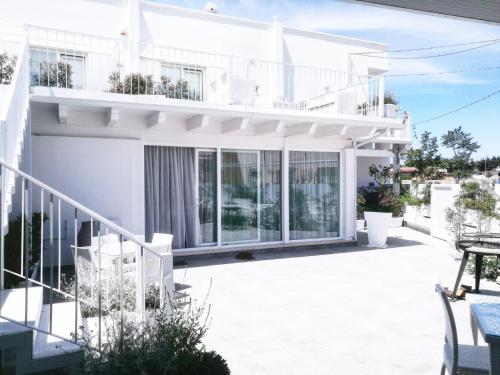 a white house with large windows and a patio at Arneo Terra del Sole in Torre Lapillo