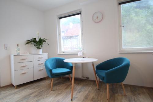 Zimmer mit 2 Stühlen, einem Tisch und einer Uhr in der Unterkunft Moderne, helle 1 Zimmer-Wohnung in Citylage in Bad Urach