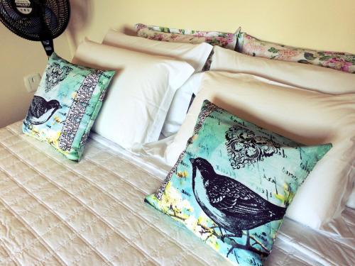 a bed with two pillows with a bird on it at Eco Pousada Quaresmeiras in Domingos Martins
