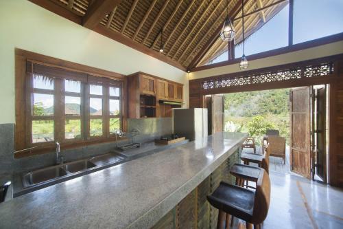 a kitchen with a counter with a sink and some chairs at Villa Kropak in Sidemen