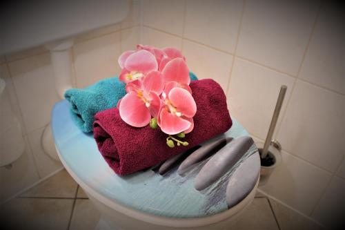 a toilet with towels and flowers on top of it at BUDGET APARTMENTS - SALZHAUSBLICK FERIENWOHNUNGEN - TOP INNENSTADT LAGE am SALZHAUS STADTZENTRUM mit HOTELBETTEN in Zittau