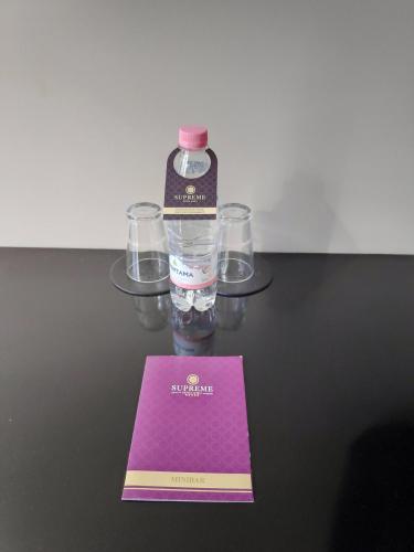 a bottle of water sitting on a table with glasses at Supreme Hotel in Golem