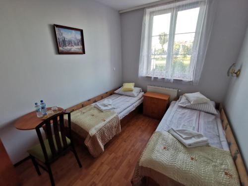 a room with two beds and a table and a window at Hotel TERESITA in Kraków