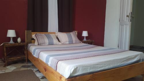 a bed in a room with two lamps on tables at Ecole Lodge Antananarivo in Mahitsy