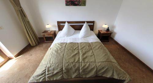 a bed in a room with two nightstands and two lamps at Pension Deutsches Haus in Braşov