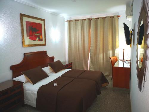a bedroom with a bed and a desk and a window at Hotel Polamar in Santa Pola