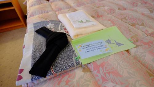 a bed with two towels and a book on it at Okuhida Garden Hotel Yakedake in Takayama