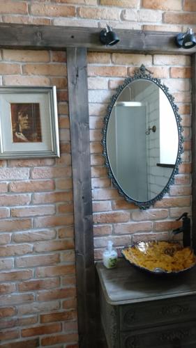 a bathroom with a mirror on a brick wall at Gościnna Prowansja in Łuków