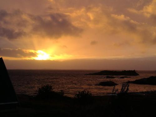a sunset over the ocean with the sun setting at Kuvågen 23 in Vågenes