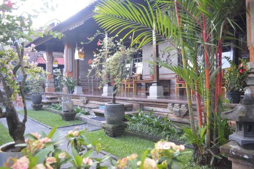 a garden with trees and plants in front of a building at Nick's Homestay in Ubud