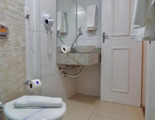 a bathroom with a sink and a toilet and a mirror at Marambaia Hotel e Convenções in Balneário Camboriú
