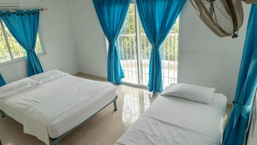 Un dormitorio con cortinas azules y una cama y una ventana. en Villa Laura, en Santa Marta