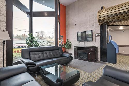 a living room with black leather furniture and a fireplace at Airport Traveller's Inn in Calgary