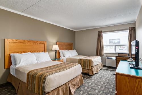 a hotel room with two beds and a television at Airport Traveller's Inn in Calgary