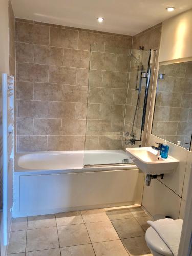 a bathroom with a bath tub and a sink at The Paramount, Swindon in Swindon