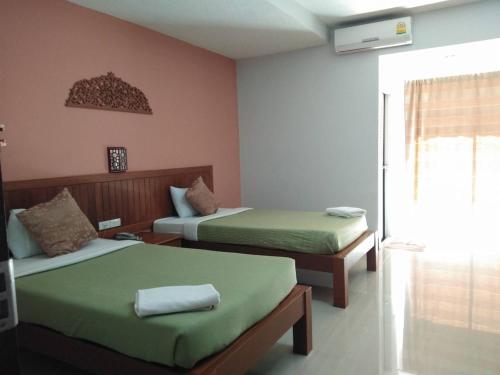 Habitación con 2 camas con sábanas verdes y ventana en Butnamtong Hotel en Lampang