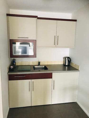 a kitchen with white cabinets and a sink and a microwave at Tresori Motor Lodge in Akaroa