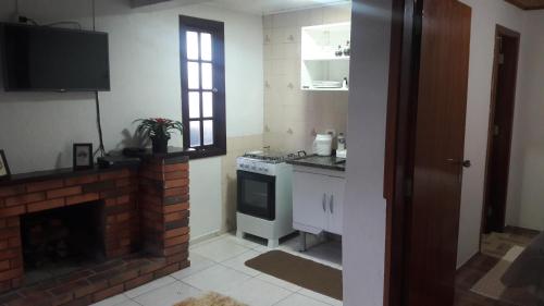 a kitchen with a stove and a brick fireplace at Chalé Topázio in Monte Verde