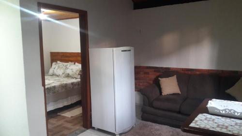 a living room with a refrigerator and a couch at Chalé Topázio in Monte Verde
