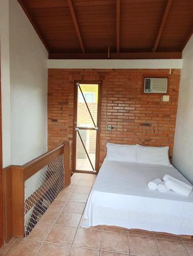 a bedroom with a bed and a brick wall at Pousada Latitude 27 Bombinhas in Bombinhas