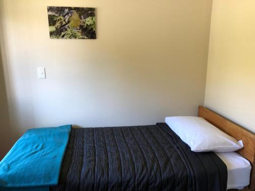 a bedroom with a bed with a blue blanket on it at Stewart Island Backpackers in Half-moon Bay