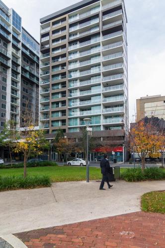 a man walking down a sidewalk in front of a tall building at Lux 2BR Apt on Hindmarsh SQ-Pool-Gym-Sauna-Parking in Adelaide