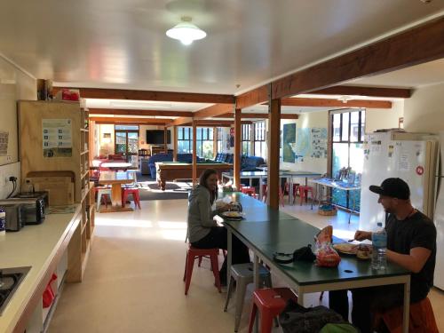 two people sitting at a counter in a kitchen at Stewart Island Backpackers in Half-moon Bay